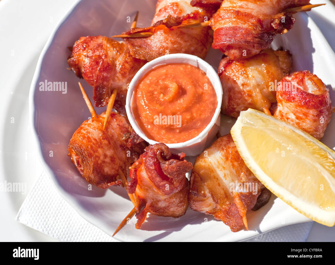 Deep fried bacon wrapped scallops with seafood sauce and lemon Stock