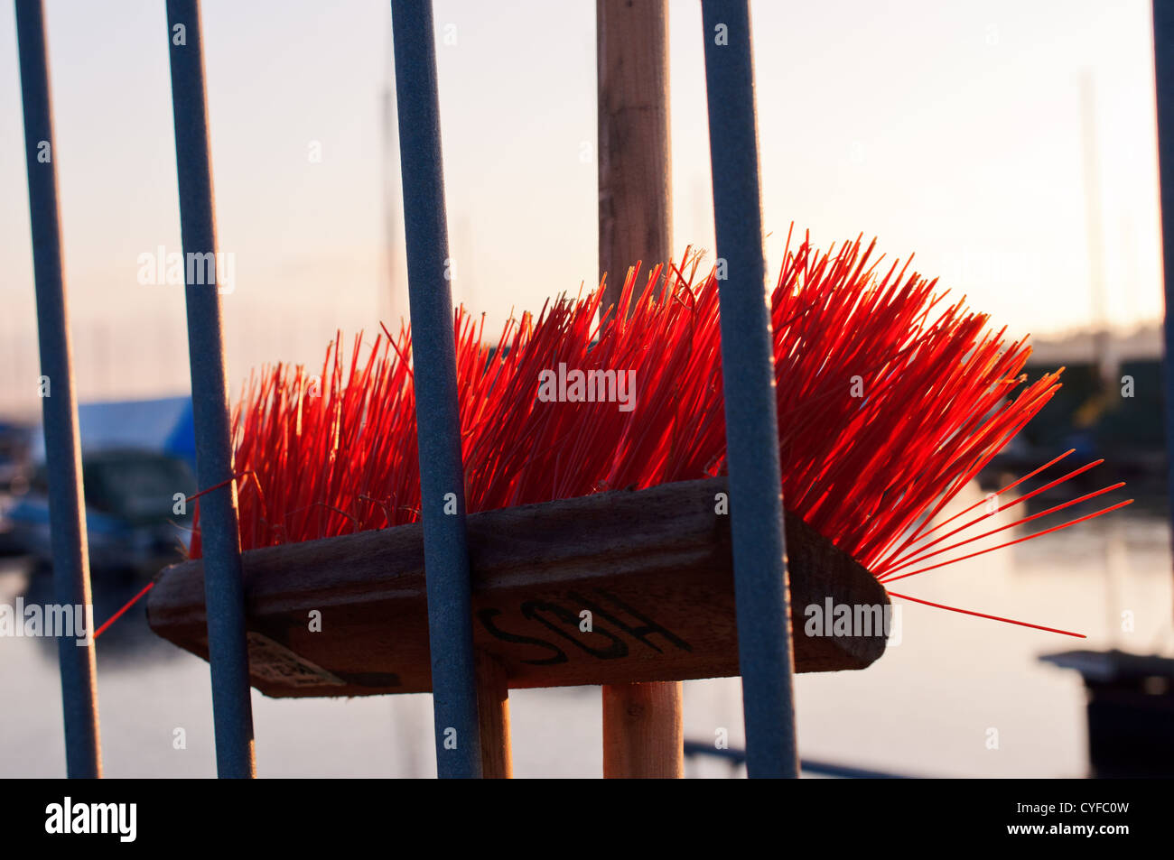 Red mop behind fence broom highlighted Stock Photo Alamy