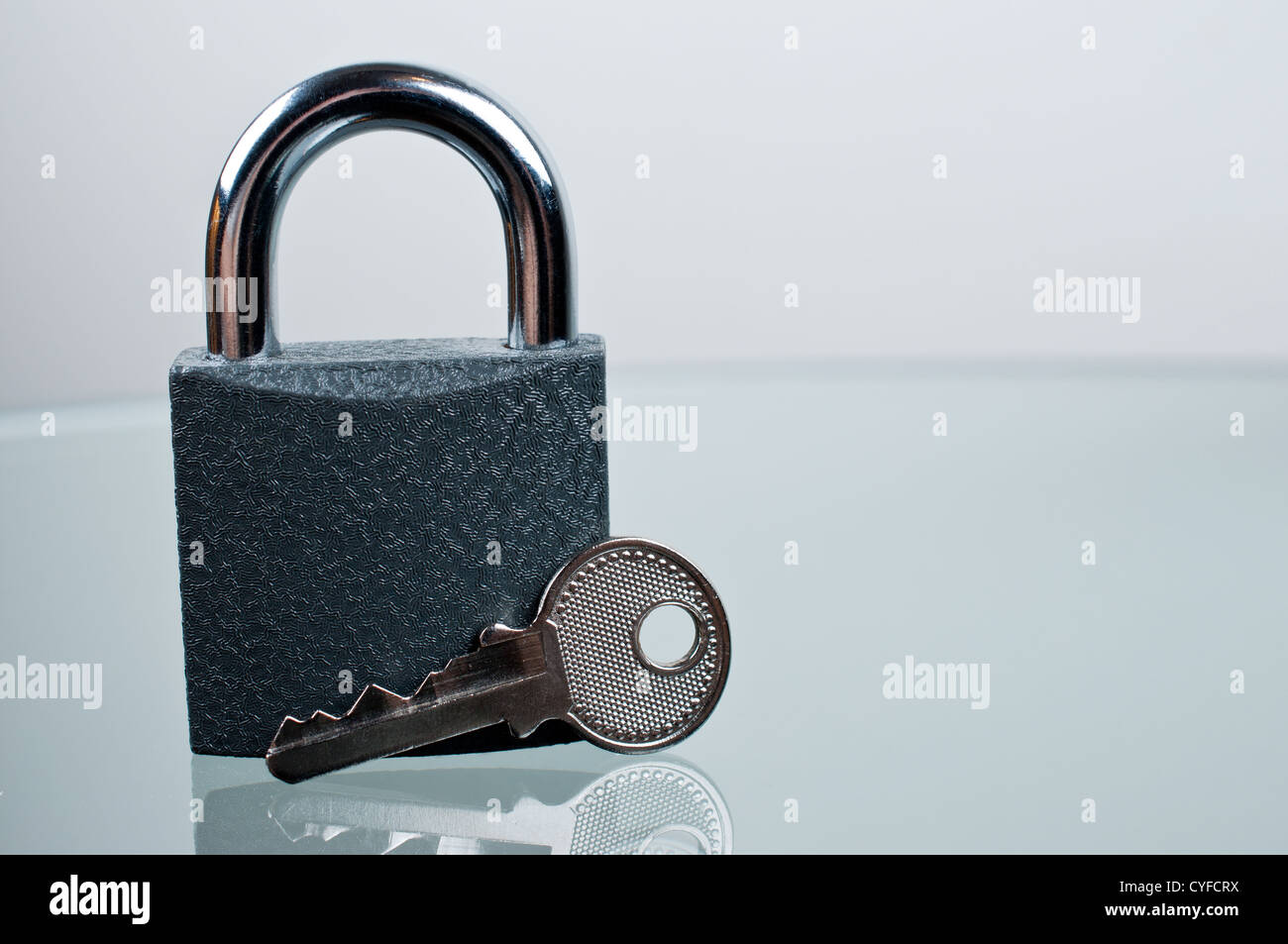 Padlock with a key on grey background Stock Photo - Alamy