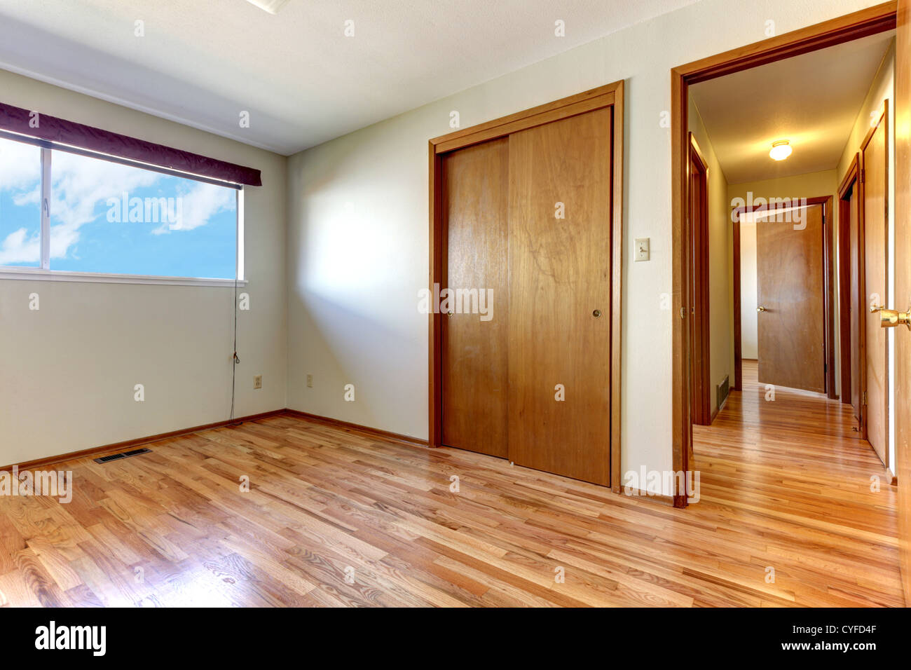 Empty Bedroom With Shiny Hardwood Floor And Open Door To Hallway