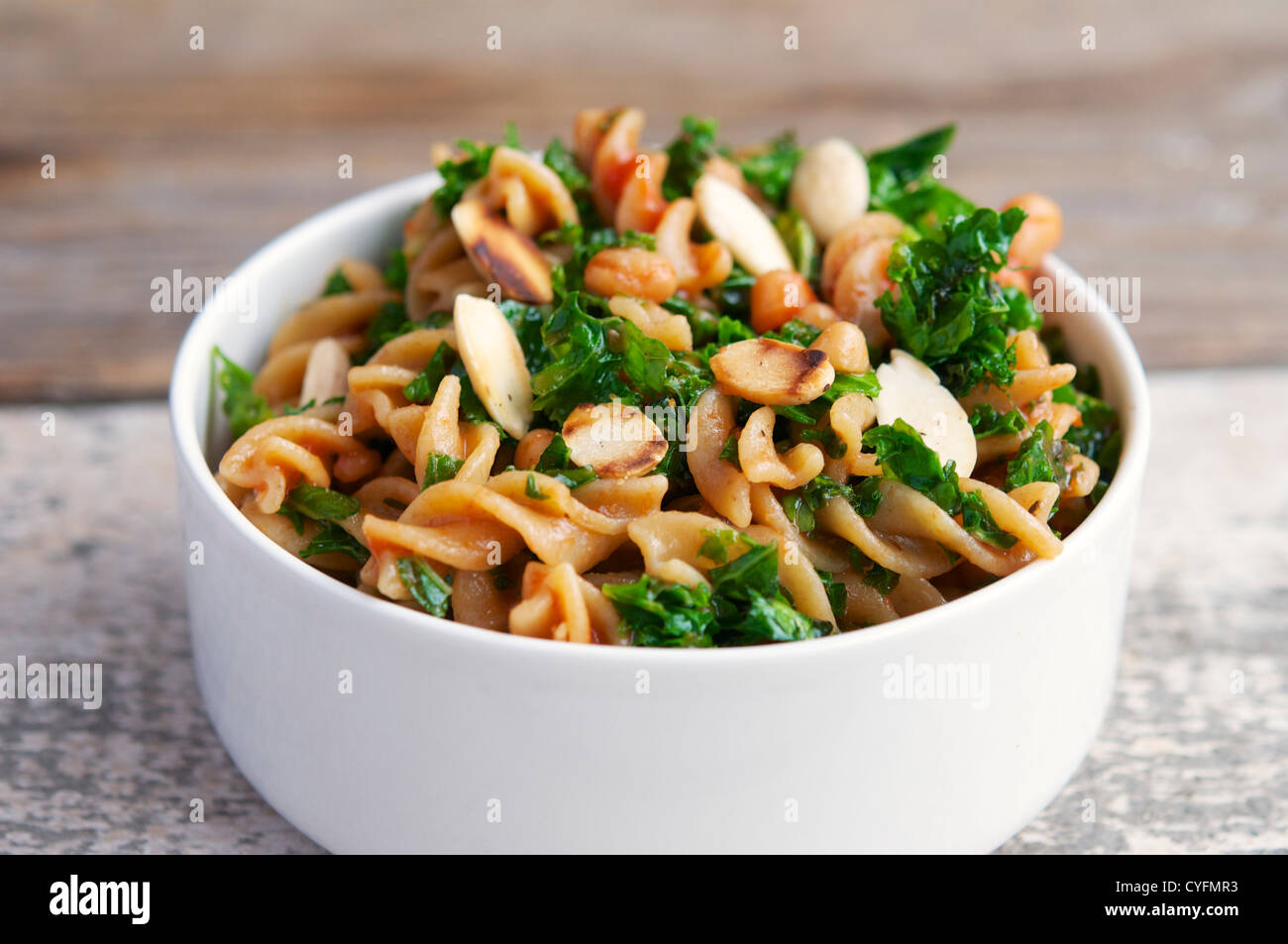 White bowl with kale, white beans and almonds pasta. Stock Photo