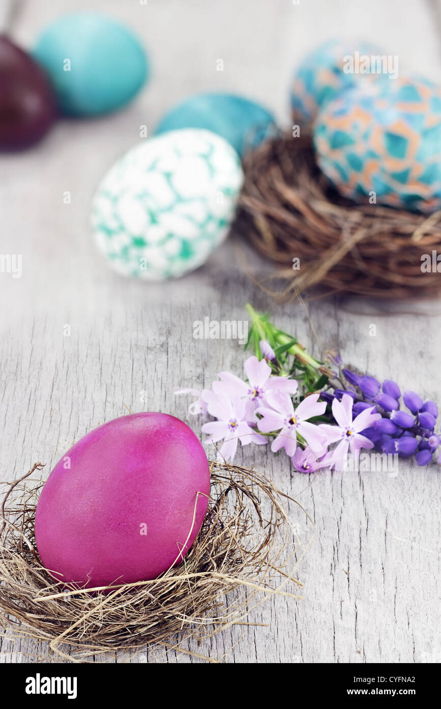 Beautiful Easter egg in a small nest with spring flowers and more eggs in background. Selective focus on egg in foreground. Stock Photo