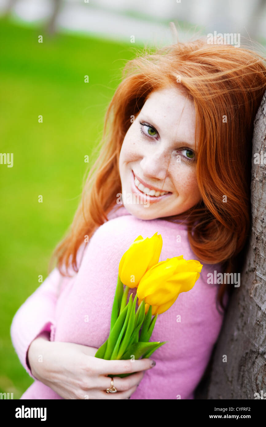 Portrait of beautiful smiling girl with spring flowers posing in park ...