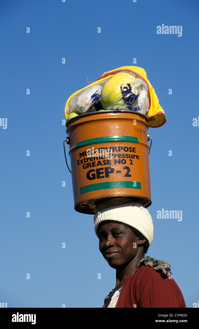 Zimbabwe, near Hwange, Woman carrying bucket on head. Stock Photo