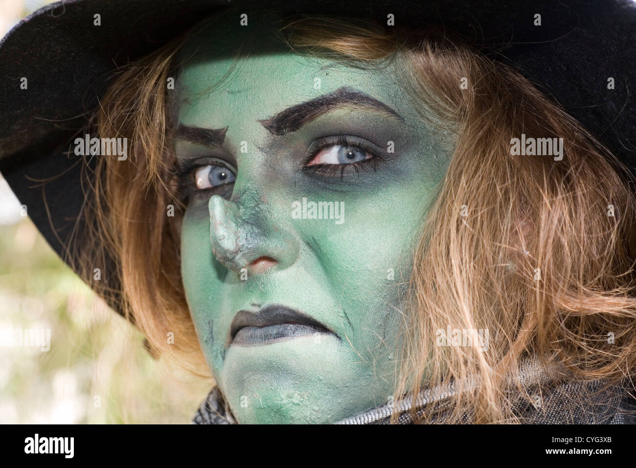 Girl dressed up with make up and prosthetic nose to look like a wicked green witch. Stock Photo