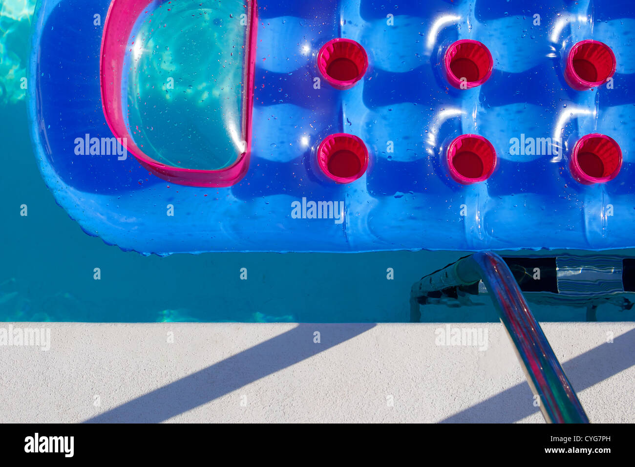 Abstract image - Blue & red inflatable mattress floating pool side. Stock Photo