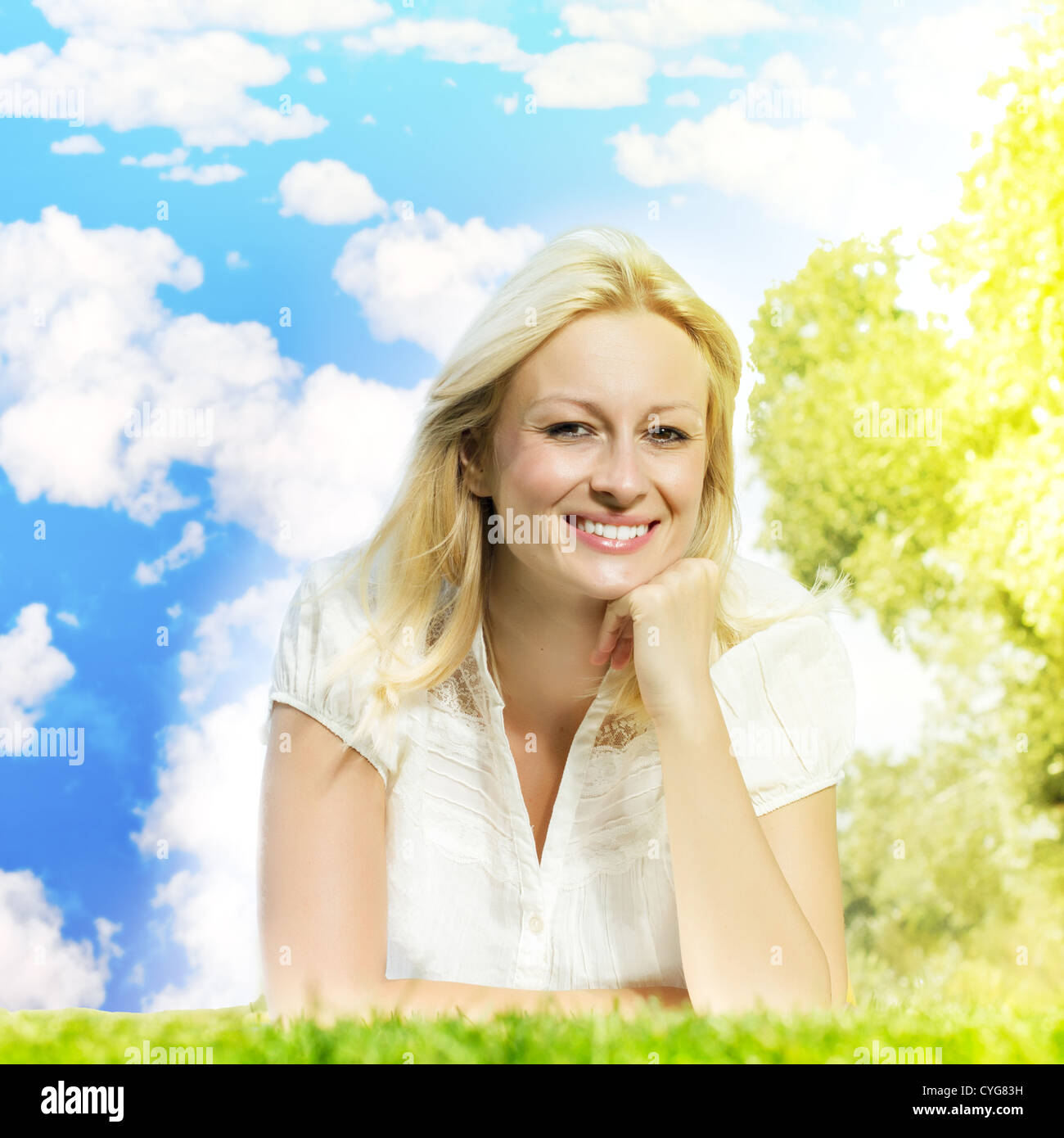 Happiness smiling blond woman relaxing on green against blue sky with ...