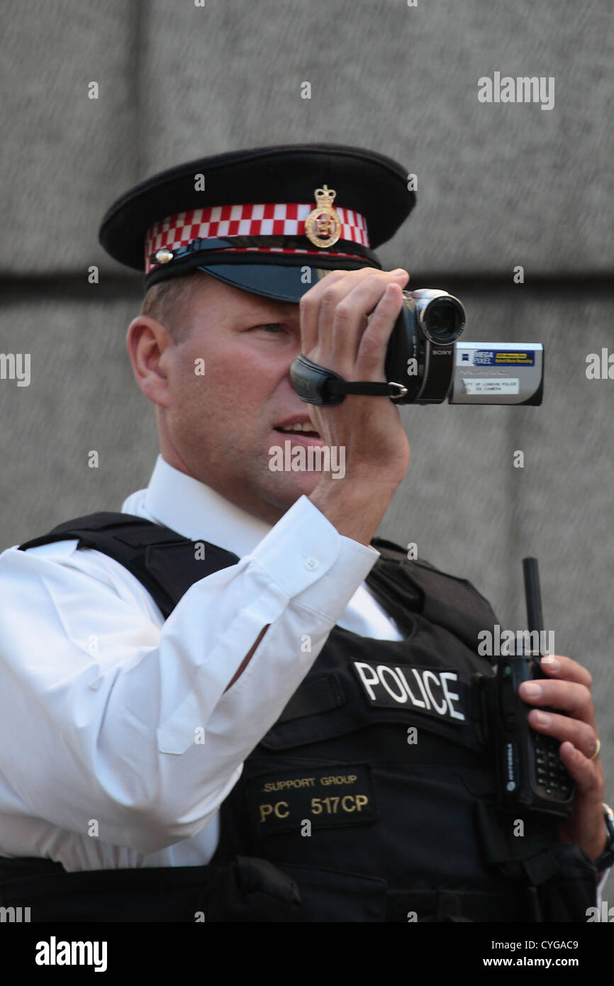 A city of London police officer video records protesters at a ...