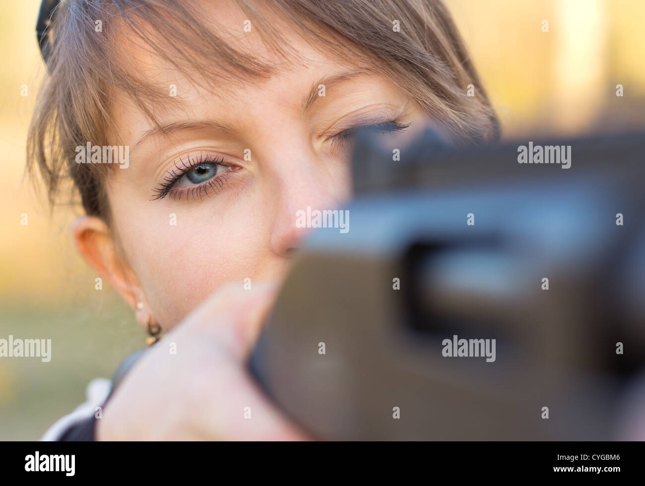 A young girl with a gun for trap shooting and shooting glasses aiming