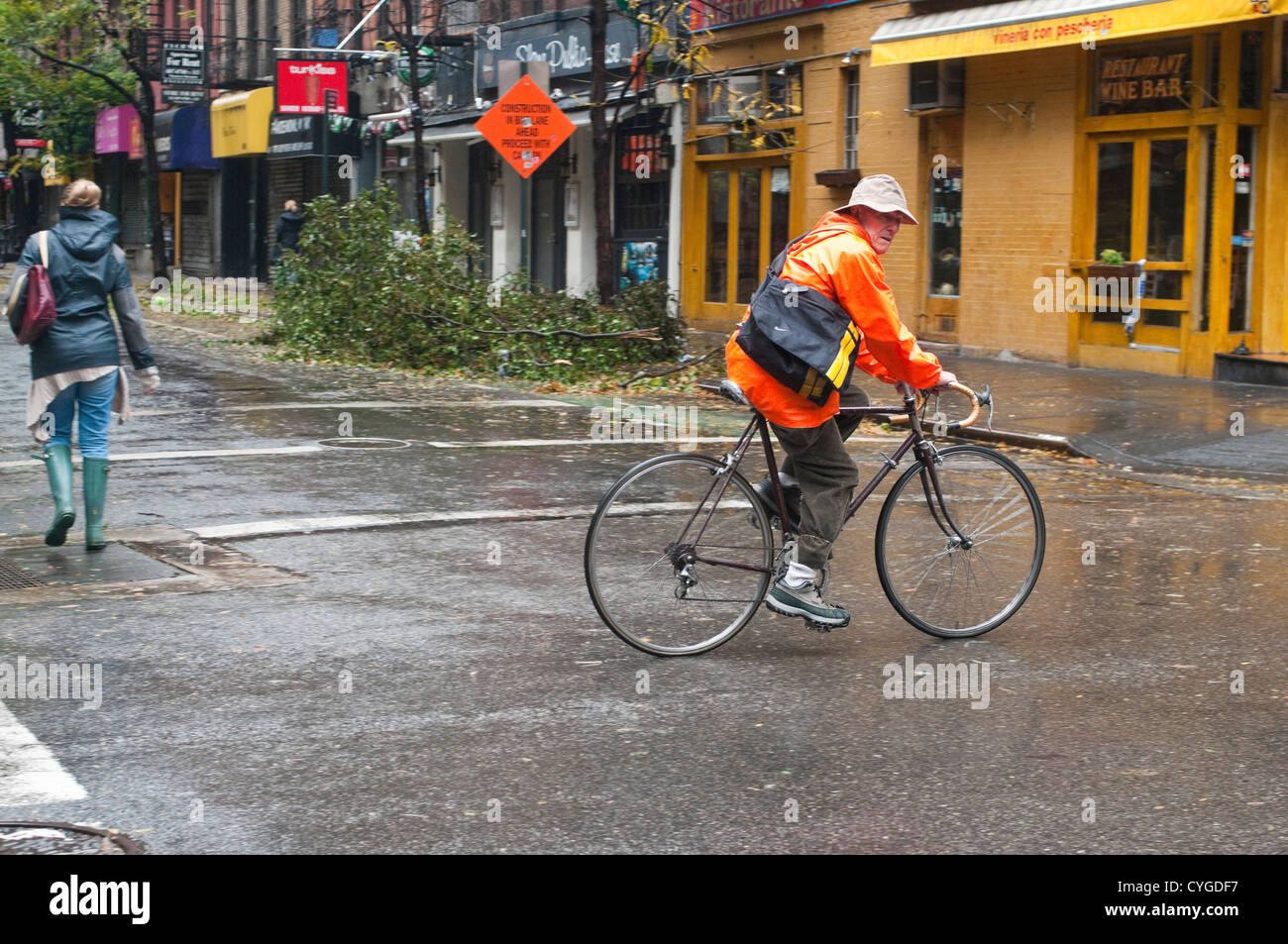 New York, NY 30 October 2012 Man rides a bicycle while a woman walks