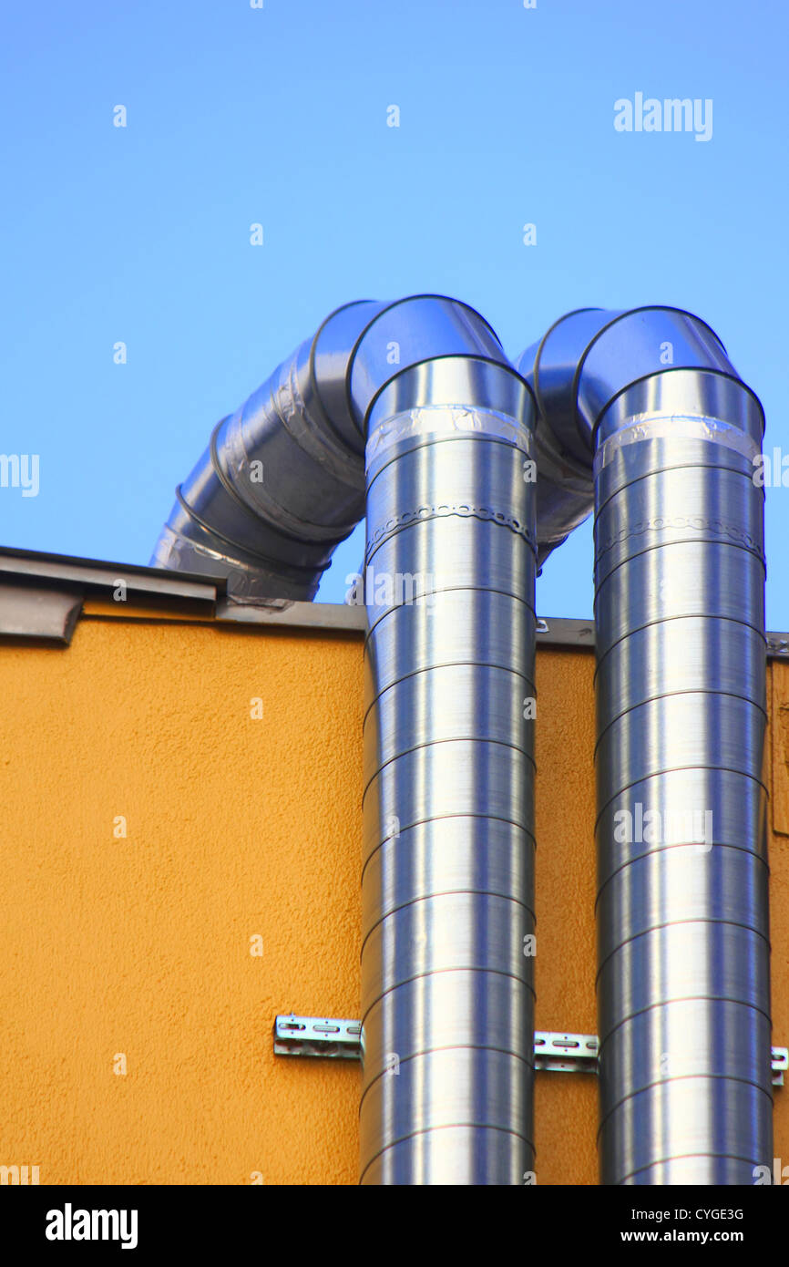 Two ventilation ducts crawling on a yellow wall Stock Photo