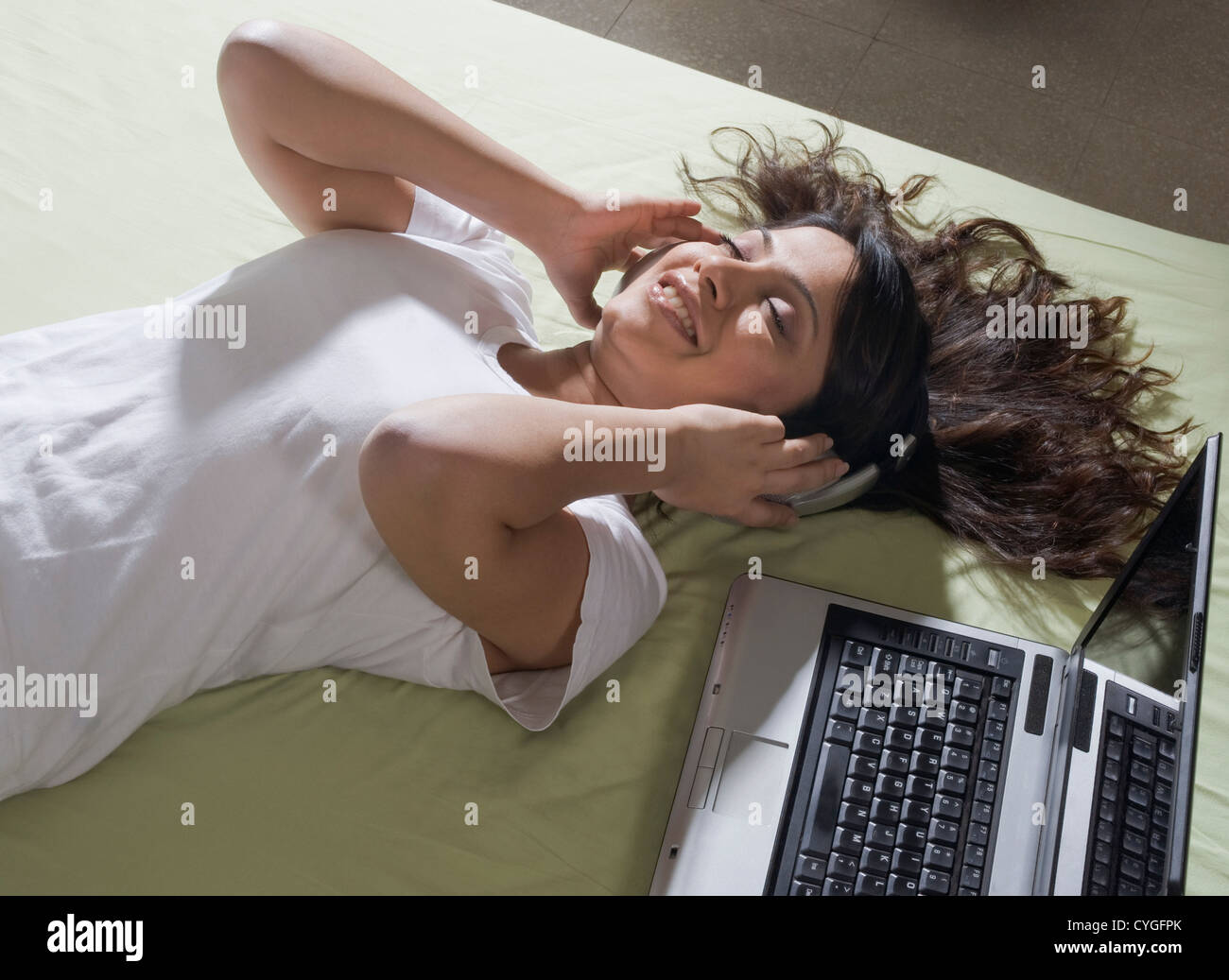 Woman lying on the bed and listening to music Stock Photo - Alamy