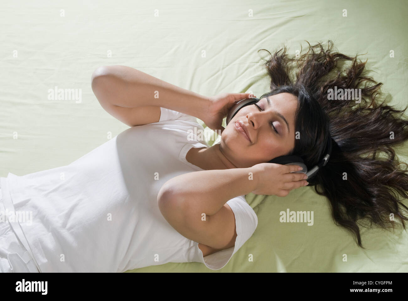 Woman lying on the bed and listening to music Stock Photo - Alamy