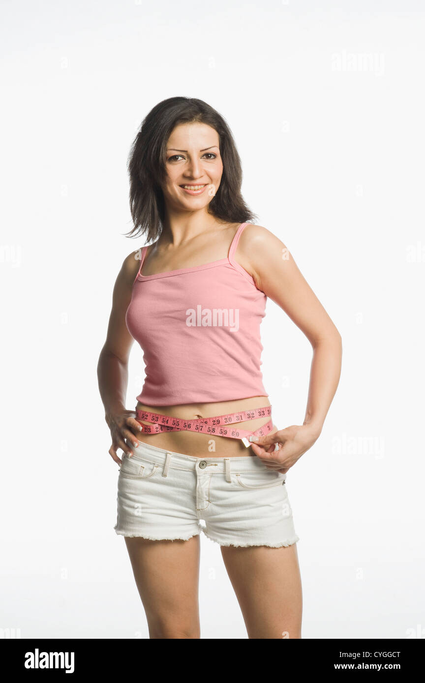 Woman measuring her waist with a tape measure Stock Photo