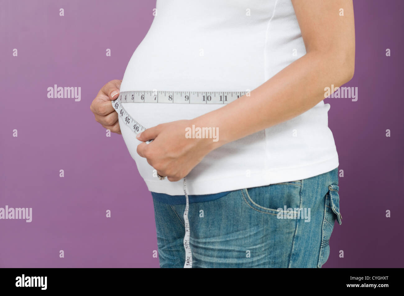 Pregnant woman measuring her abdomen with a tape measure Stock Photo