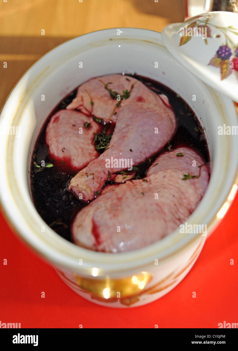 Chicken legs marinating in red wine in casserole dish to make Coq au