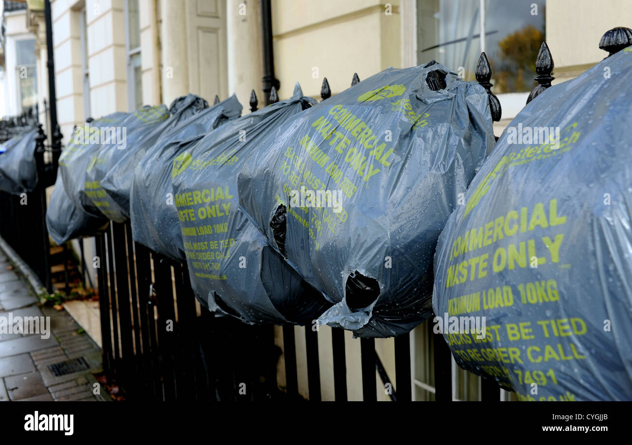 Commercial Waste Only rubbish bags hanging on iron railings fence in