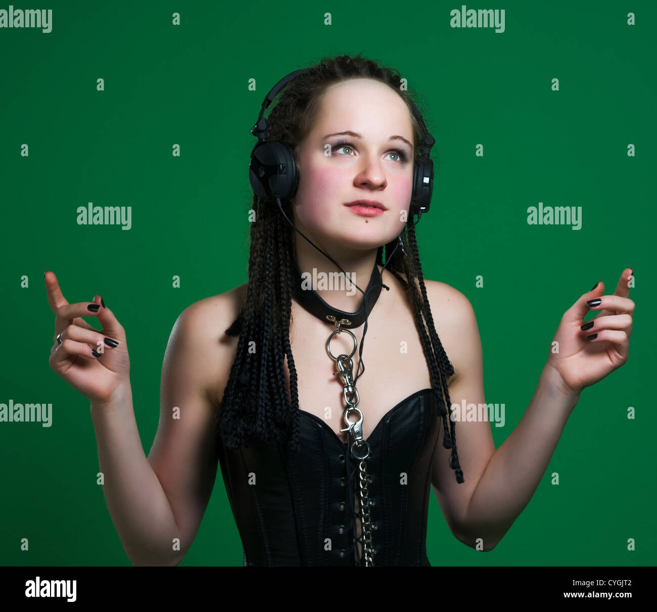 Sexy gothic woman with dreads wearing BDSM outfit listening to the music on  green background Stock Photo - Alamy