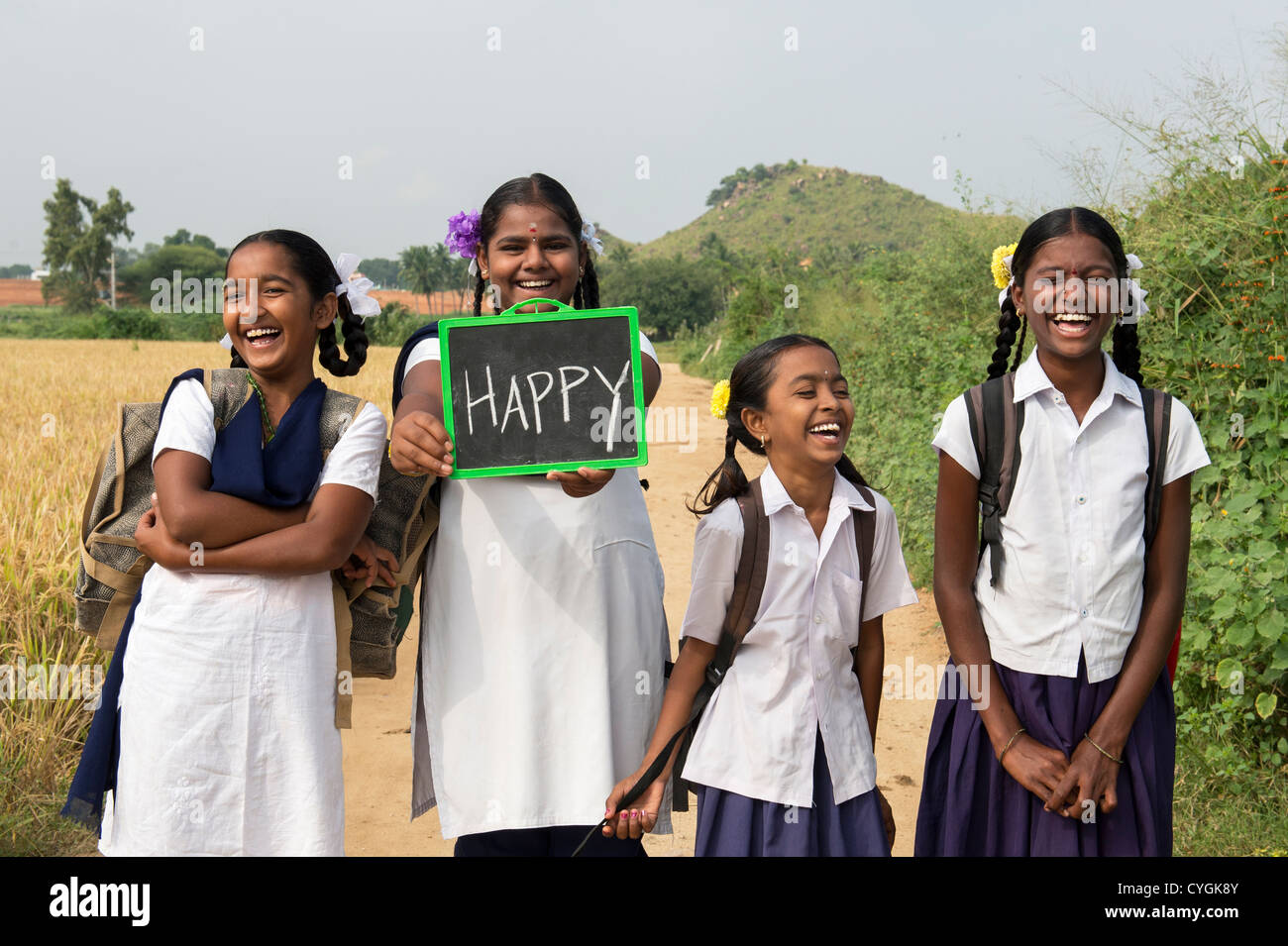 Laughing Indian school girls holding a chalkboard with happy written on it. Andhra Pradesh, India Stock Photo