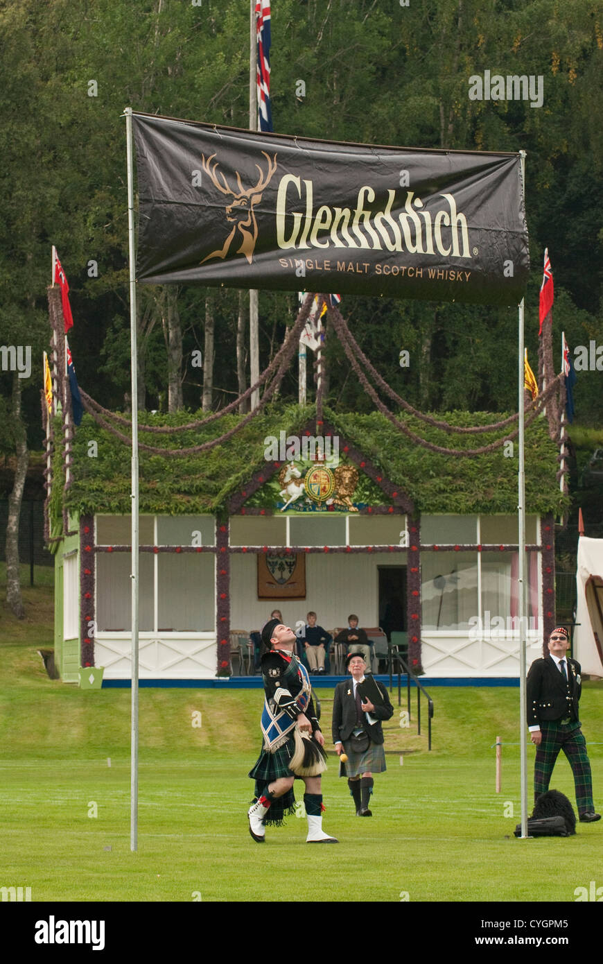 Man in traditional Scottish dress looking up at Glenfiddich whisky banner, Braemar gathering Stock Photo