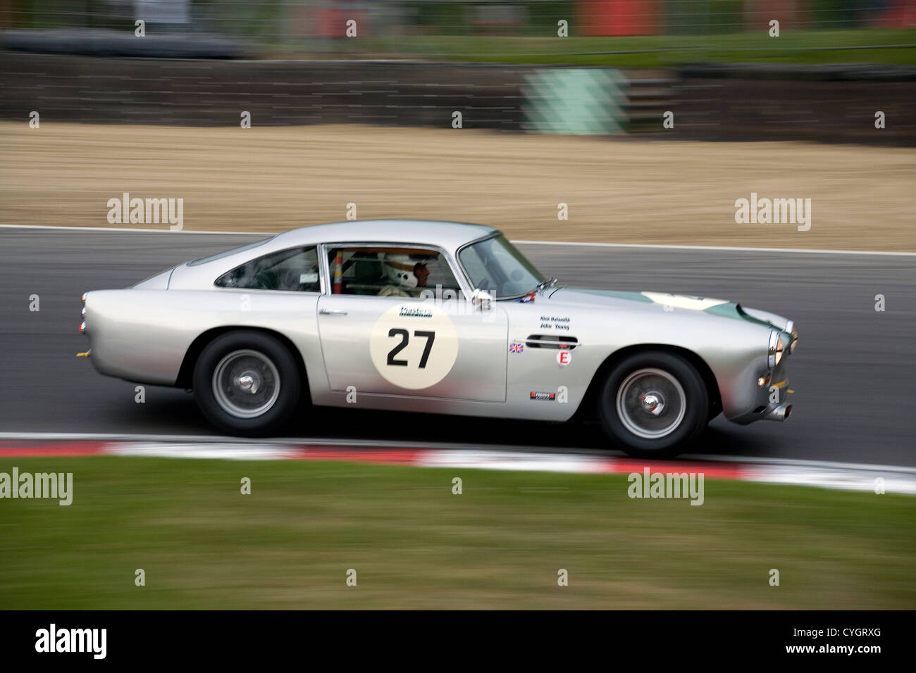 A silver Aston Martin racing car driving on Brands Hatch racing track ...