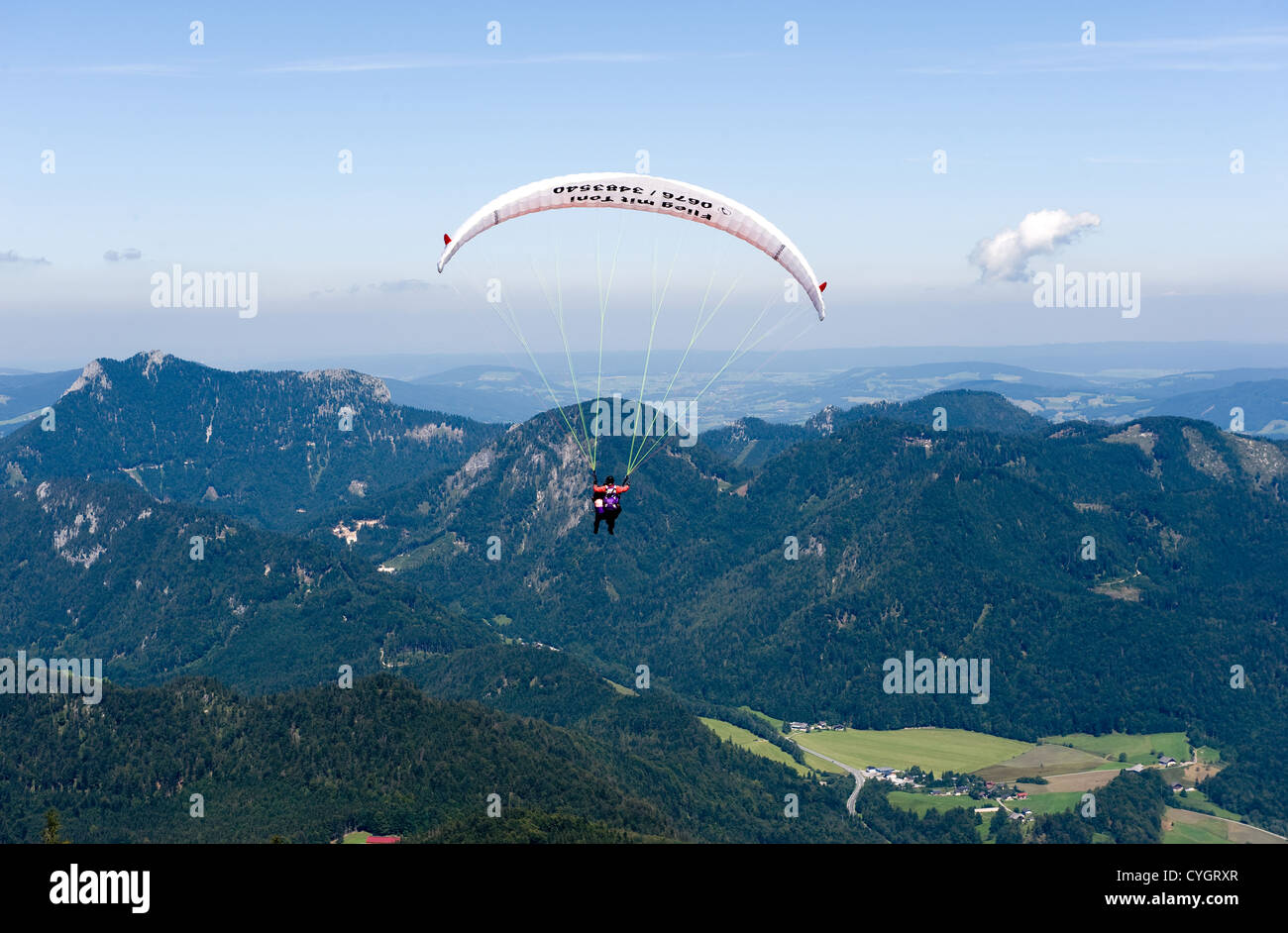 A paraglider is flying of the mountain down to the city of St.Gilgen on the banks of the Wolfgangsee. Stock Photo