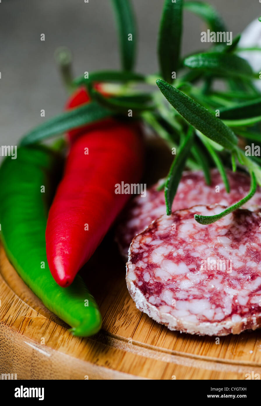 Peper salami and rosemary on cutting board close up Stock Photo