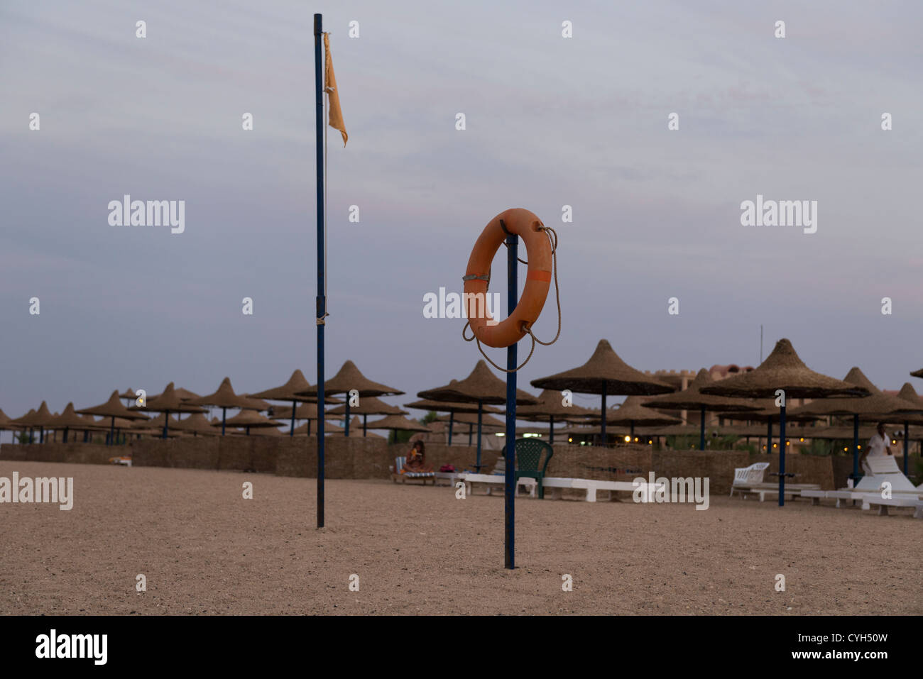 Evening at the beach. Flag pole and life buoy in foreground. Stock Photo