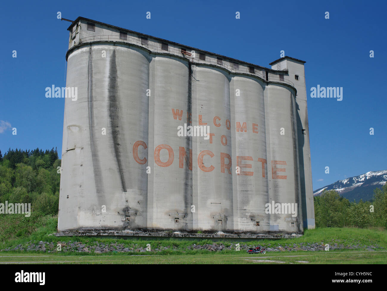 A motorcycle is dwarfed by the giant concrete grain silos of Concrete, Washington, USA. Stock Photo