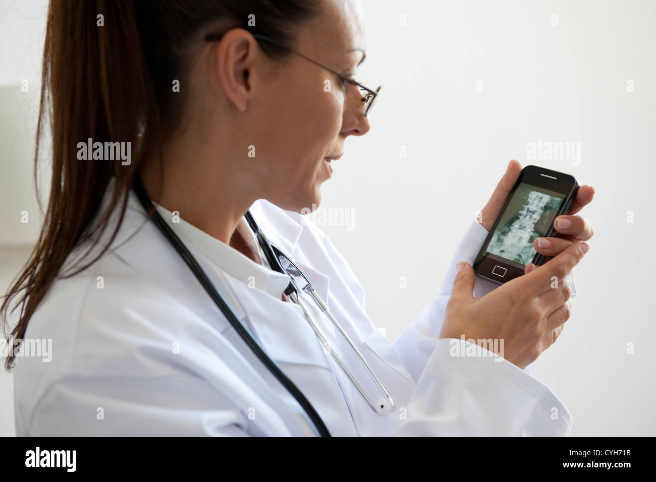 female doctor looking at x-ray on smartphone Stock Photo