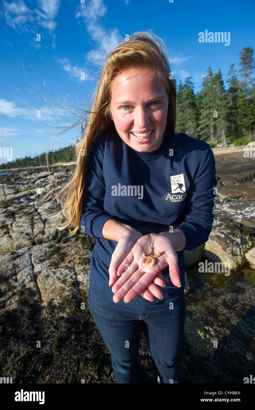 Woman holding starfish on coast of Acadia National Park on vacation Stock Photo