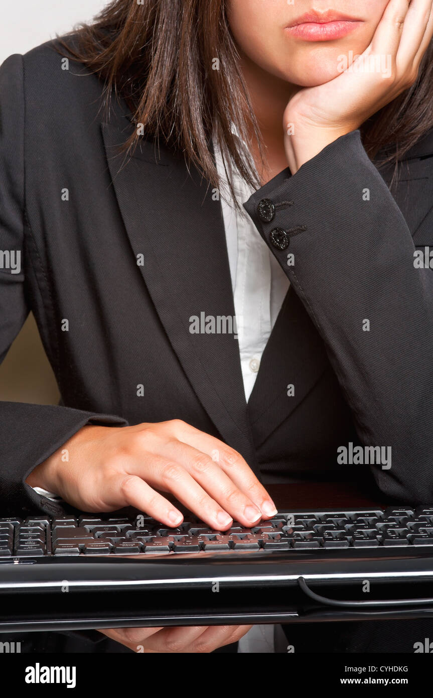 Bored businesswoman sitting at a table and typing on a keyboard Stock ...
