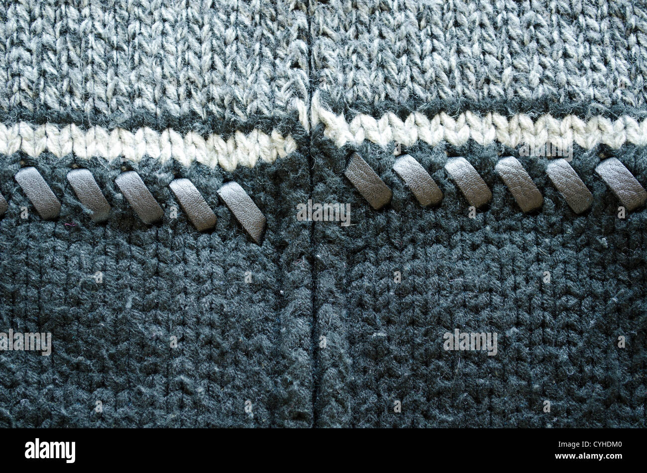 Closeup of wool knit sweater texture decorated with leather stitch. White grey and black colors background Stock Photo