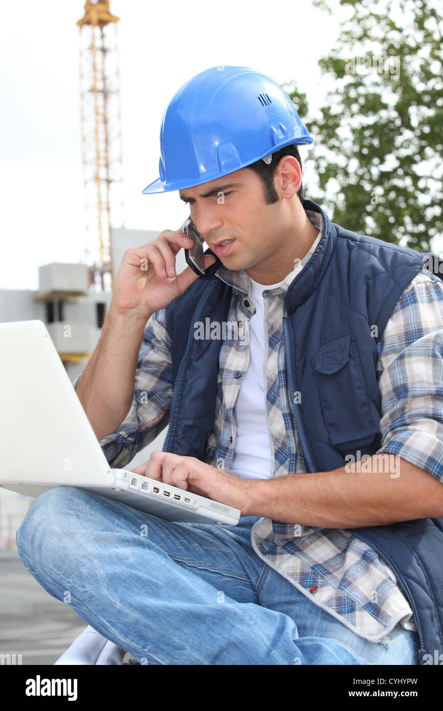 Construction worker with computer and phone Stock Photo - Alamy