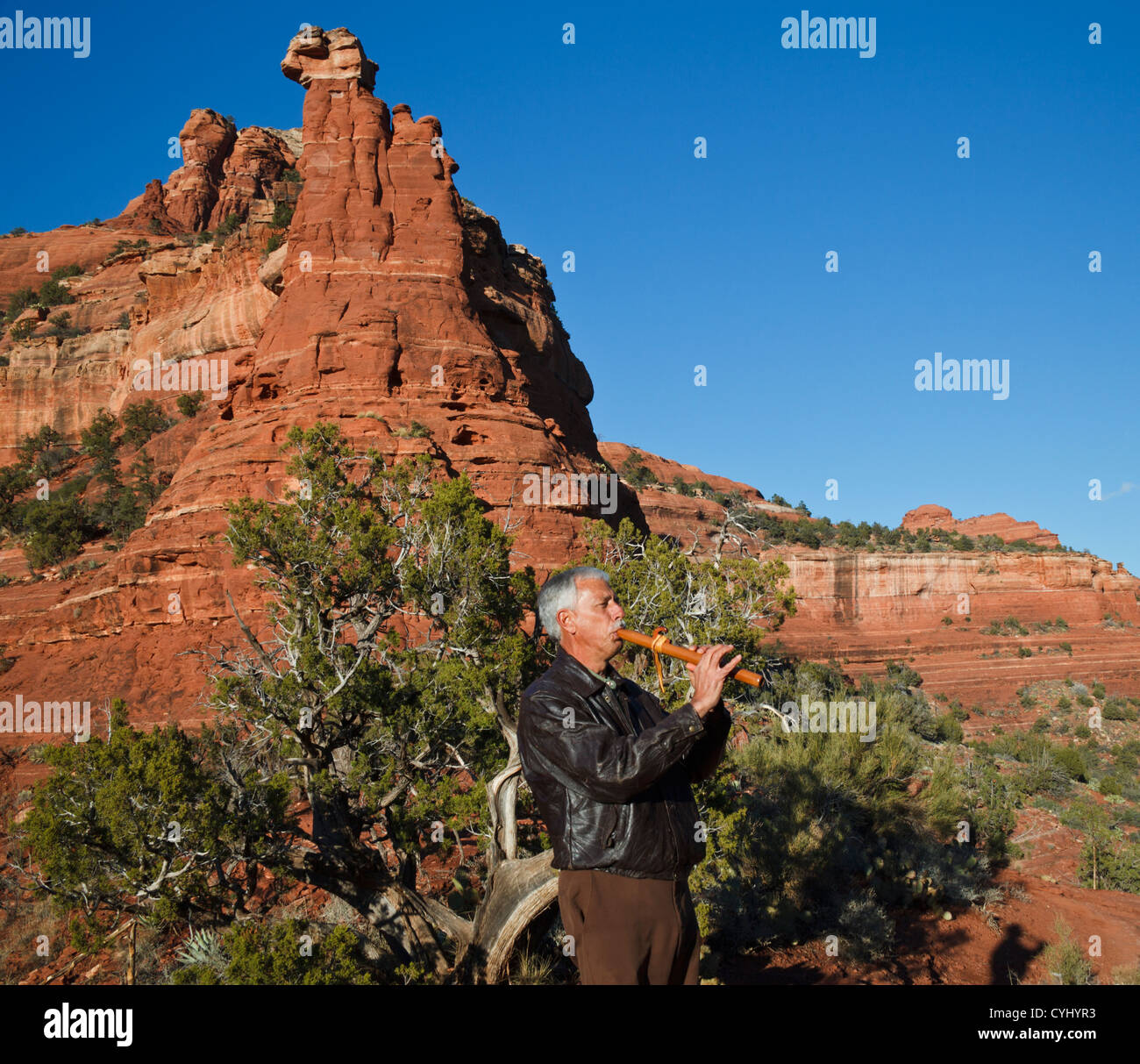 Arizona man plays Native American flute by Kachina Woman formation in Sedona, reached by hiking the Vista Trail Stock Photo