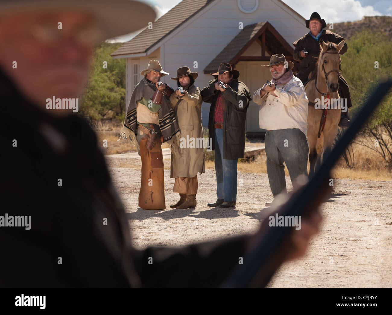 Six old west gunfighters target a man in black Stock Photo