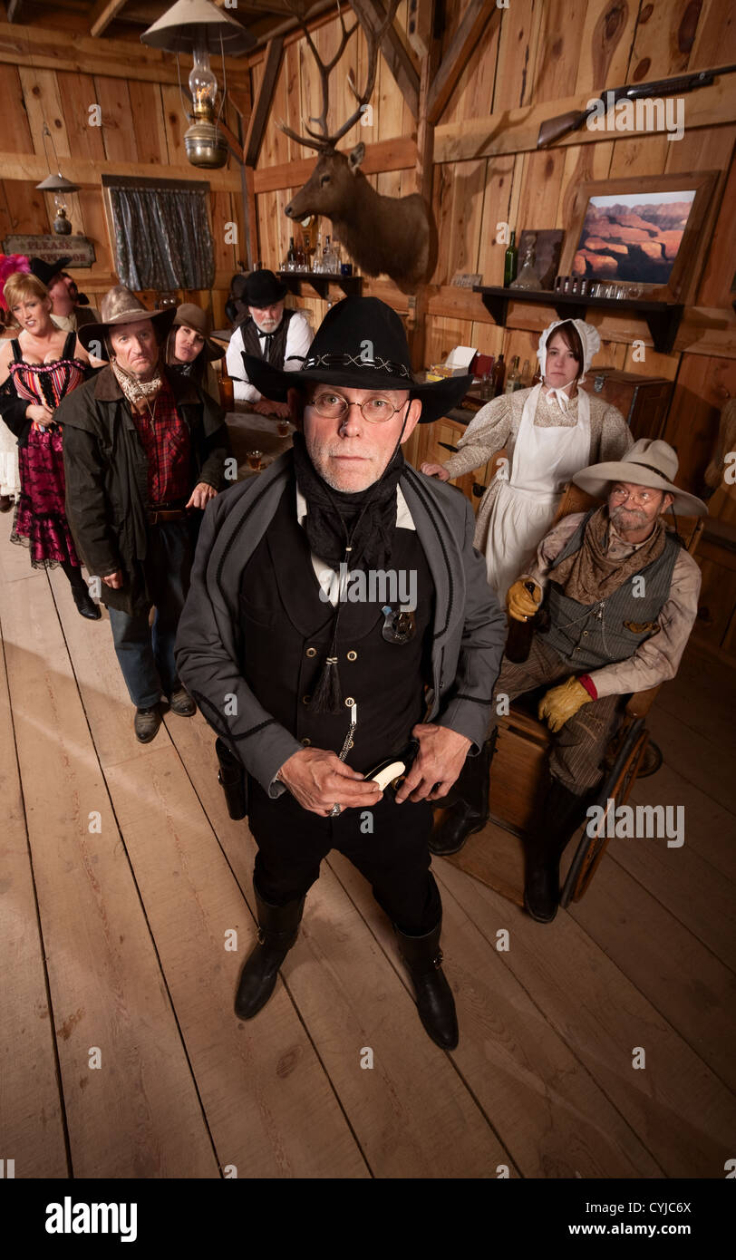 Scared customers behind tough sheriff in old west saloon Stock Photo