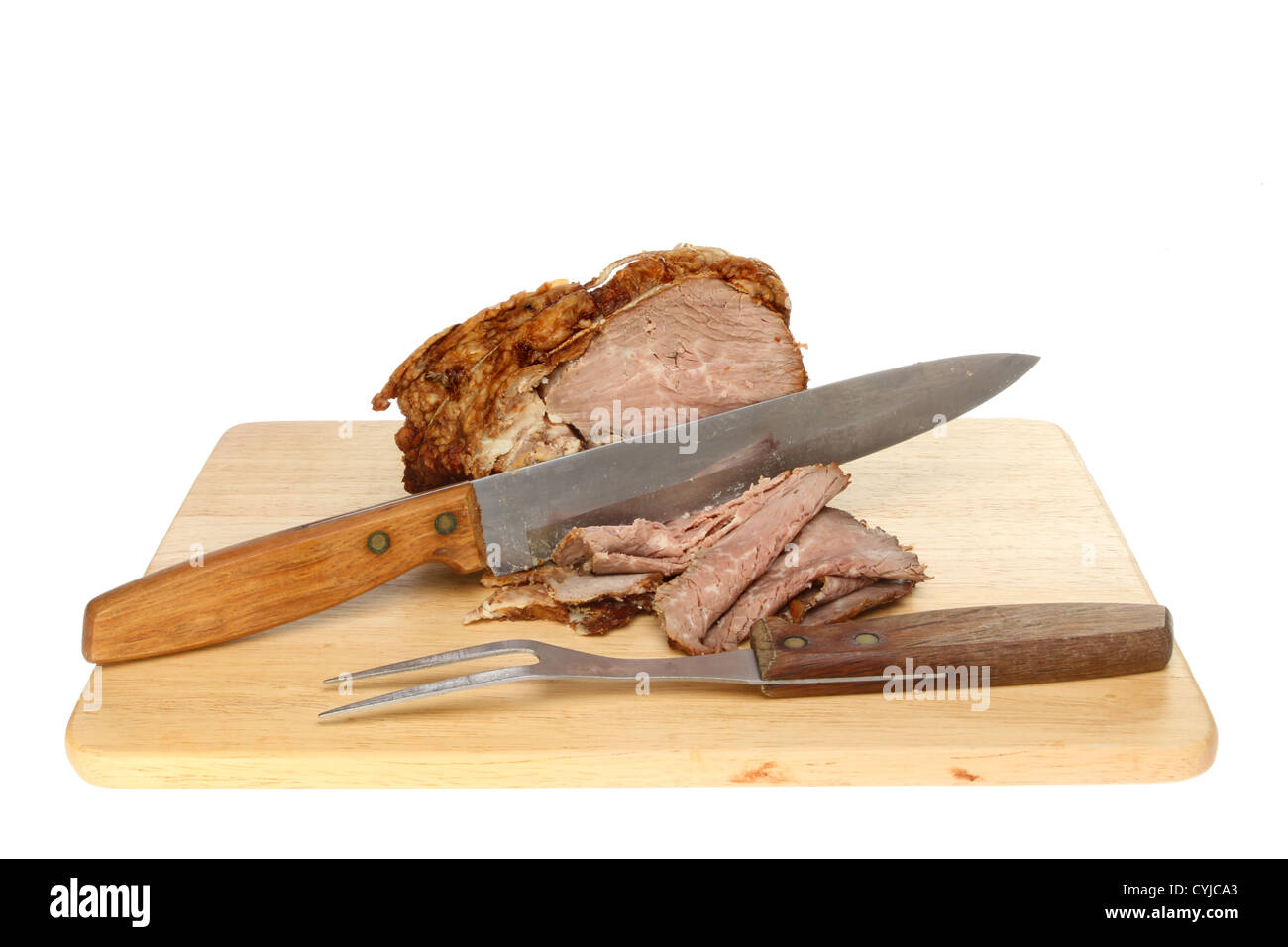 Roast beef with a carving knife and fork on a wooden board isolated against white Stock Photo