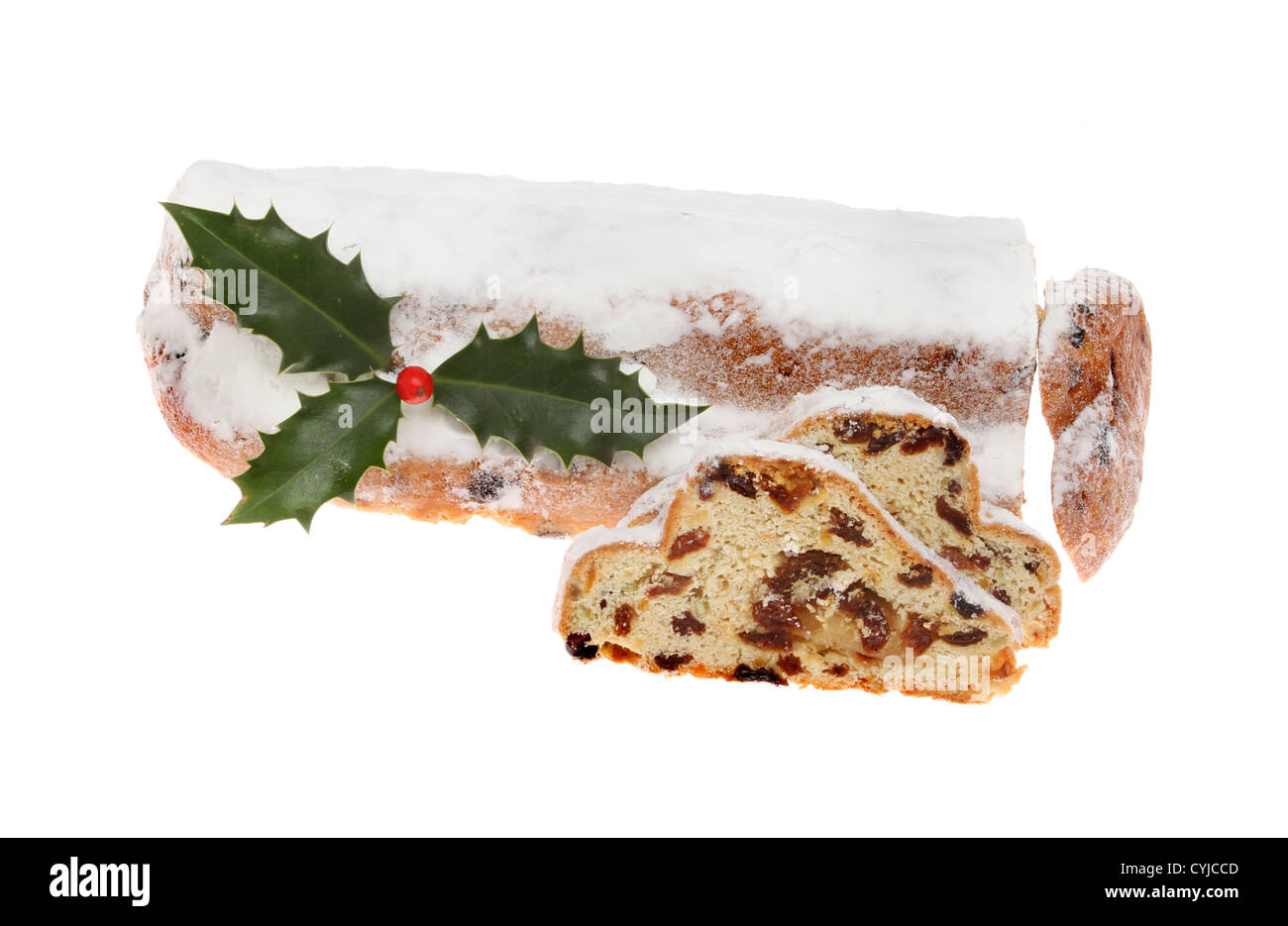 Icing sugar topped Christmas stollen with a sprig of holly and cut slices isolated against white Stock Photo