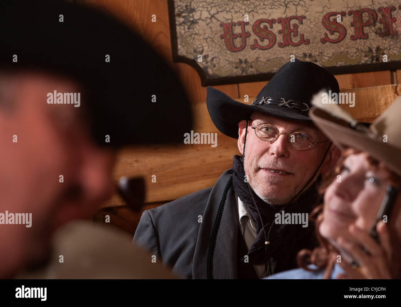 Grinning cowboy in crowded old American west saloon Stock Photo