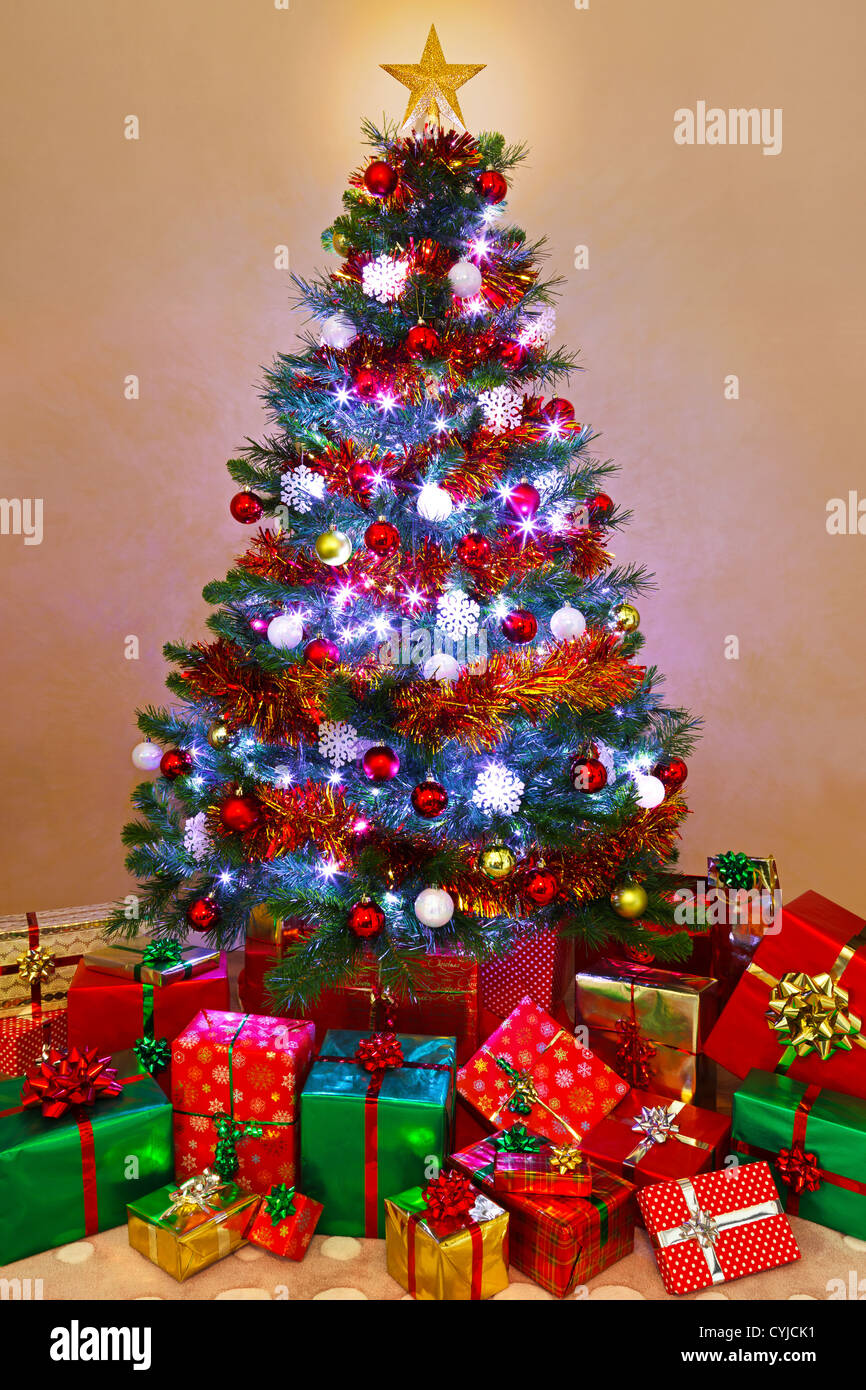 Photo of a decorated Christmas tree lit up with fairy lights and surrounded by gift wrapped presents, Santa has been! Stock Photo