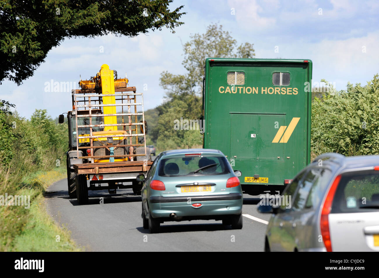 A horse box overtakes an agricultural vehicle on a road in Gloucestershire UK Stock Photo