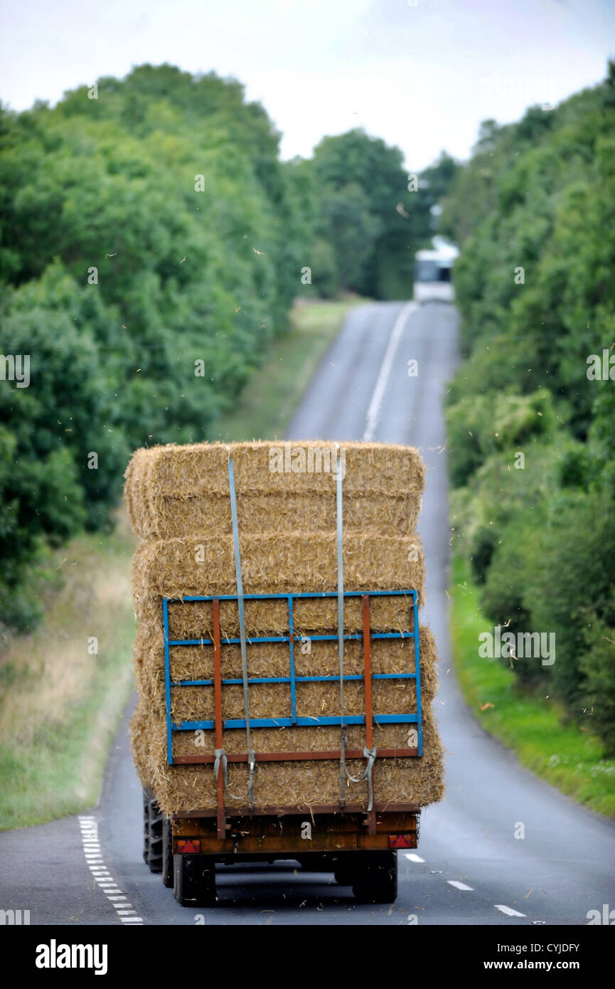A tractor towing a trailer of hay on a road in Gloucestershire UK Stock Photo