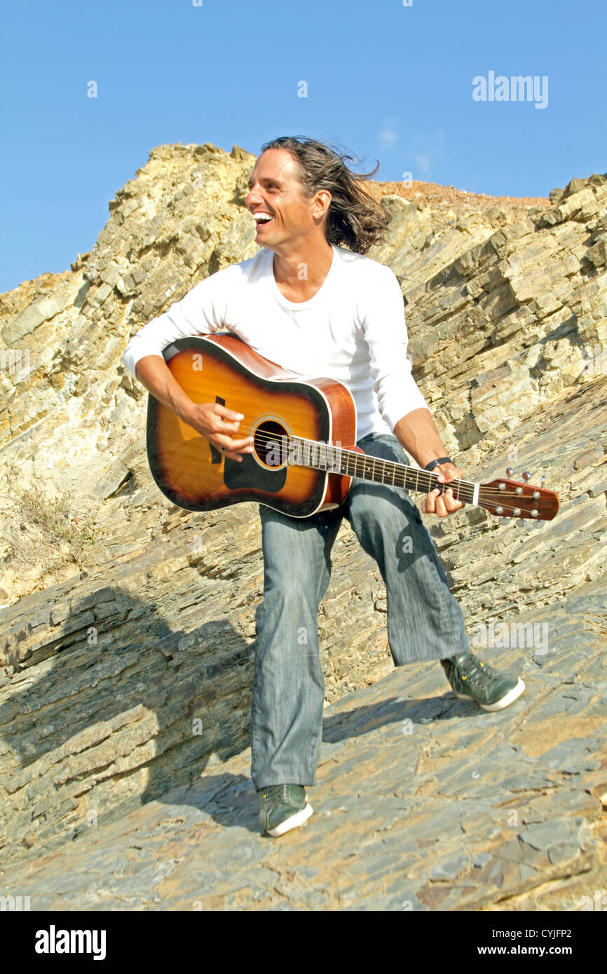 Happy guitar player on the rocks Stock Photo