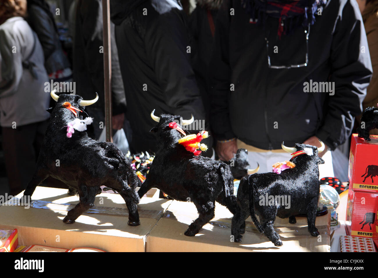 Tourists shoppers browse model black bulls for sale, El Rastro flea Sunday street market Madrid, Spain. Iconic Spanish souvenir Stock Photo