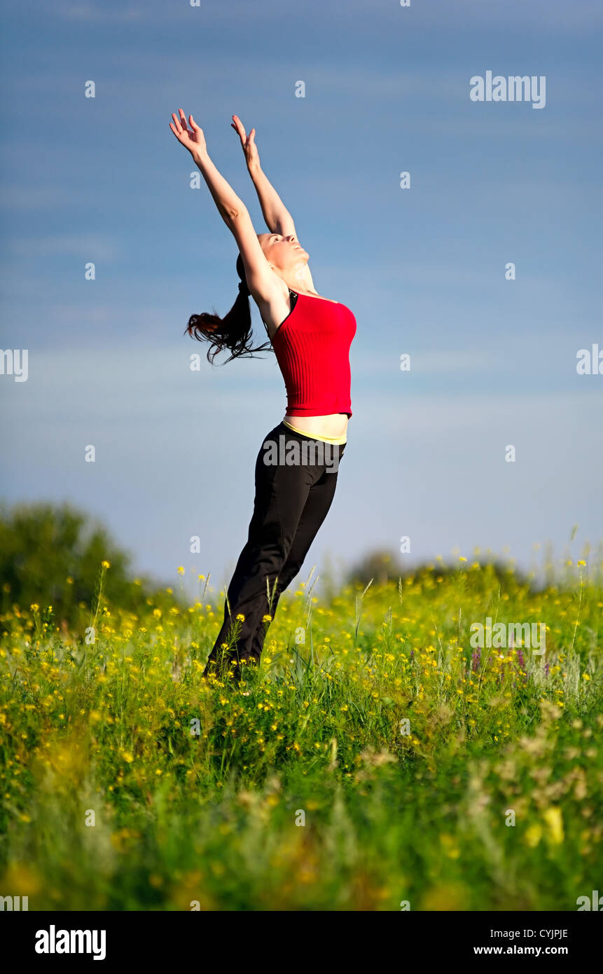 Happy young woman in sport wear jumping on a sunset field Stock Photo ...