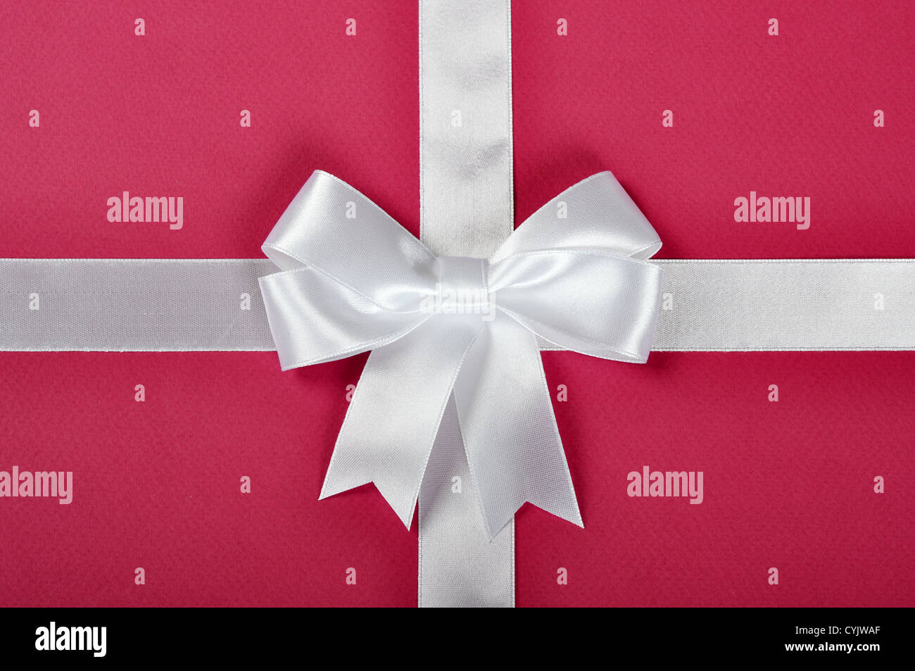 White ribbon with bow on a pink background Stock Photo - Alamy