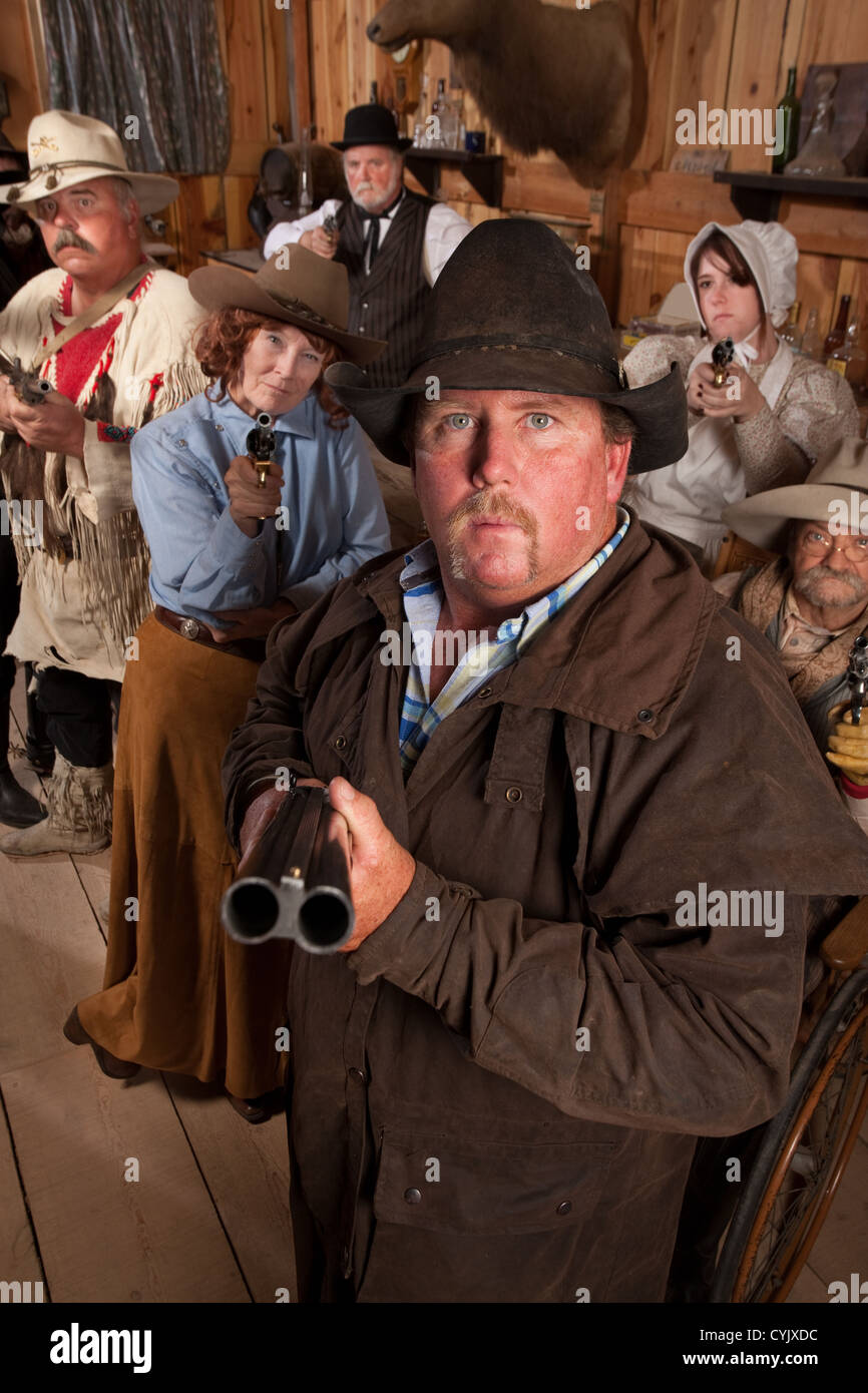 Heavyset gunslinger with shotgun in crowded old western saloon Stock Photo