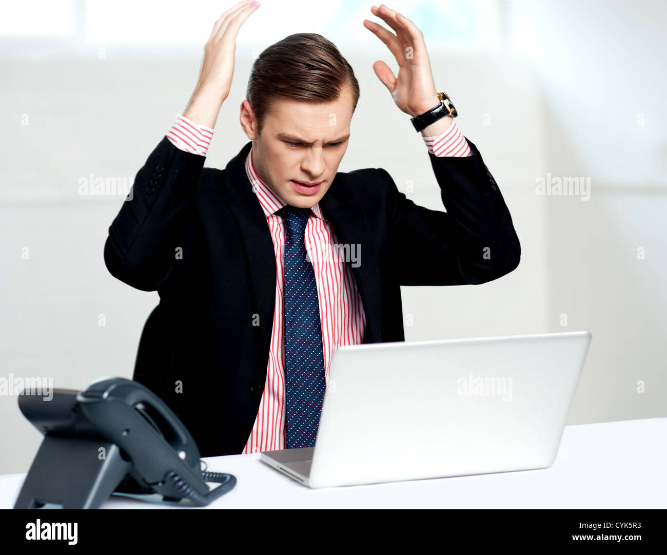 Disappointed businessman looking at laptop with hands above his head ...