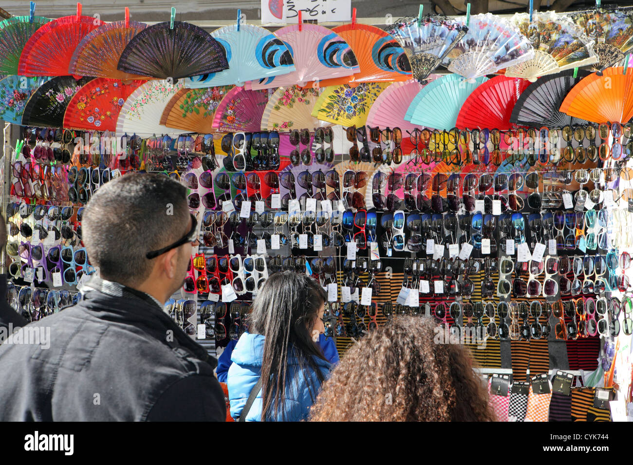 Consumers tourists browsing bargain hunting sunglasses Spanish fans, street market stall, Madrid, Spain Stock Photo